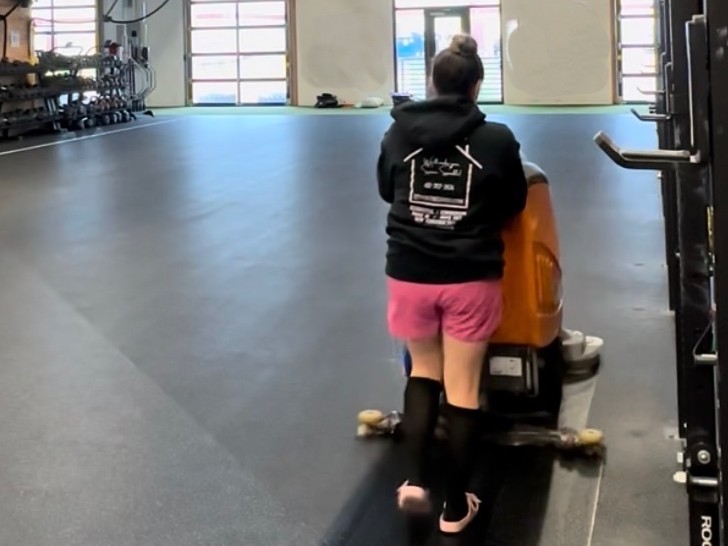 Le Vvintre team member using a floor scrubber in a fitness facility